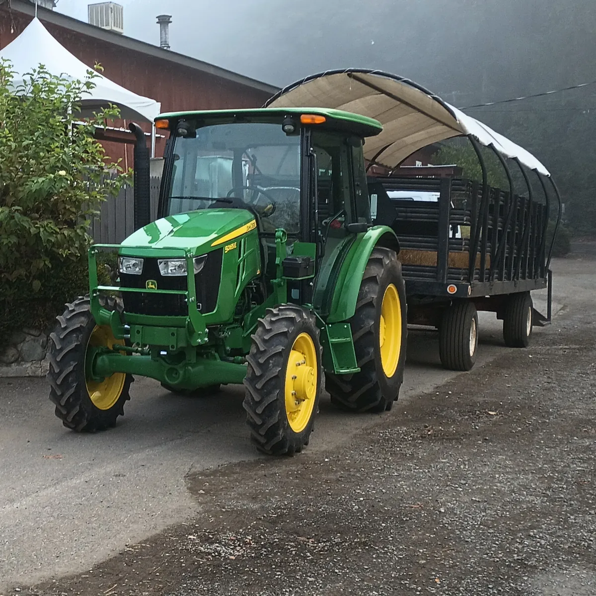 A tractor pulling a hay-filled wagon of guests along the farm road